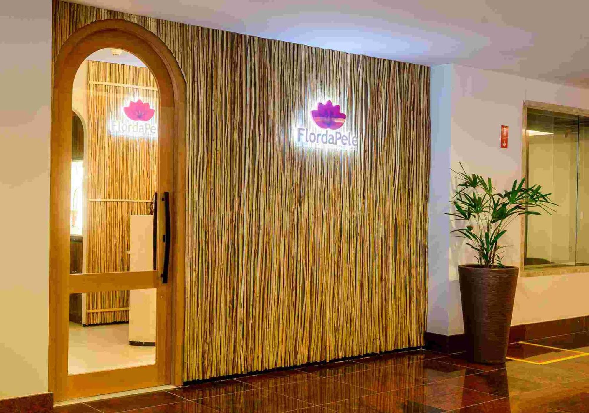 Hotel Luzeiros Sao Luis Экстерьер фото The photo shows the entrance to a spa or wellness center named "FlordaPel." The wall is decorated with natural-looking materials, resembling bamboo or reeds, giving it an organic feel. A soft-lit sign with the logo is placed above the entrance, and t