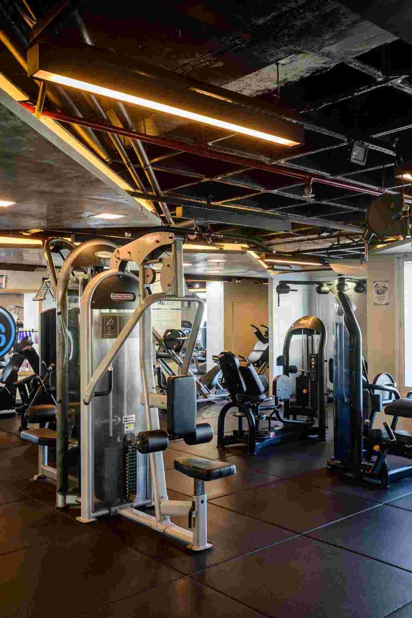 Hotel Luzeiros Sao Luis Экстерьер фото The photo shows a fitness gym with various exercise equipment. In the foreground, there are multiple machines for strength training, including cable machines and weight stations. The gym is well-lit, featuring overhead lights and windows that allow n