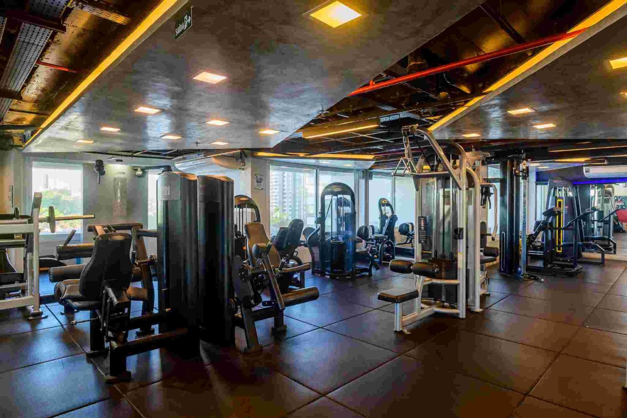Hotel Luzeiros Sao Luis Экстерьер фото The photo shows a modern gym interior featuring various workout equipment. There are several exercise machines arranged throughout the space, including strength training equipment. The room is well-lit with overhead lights and has large windows that 