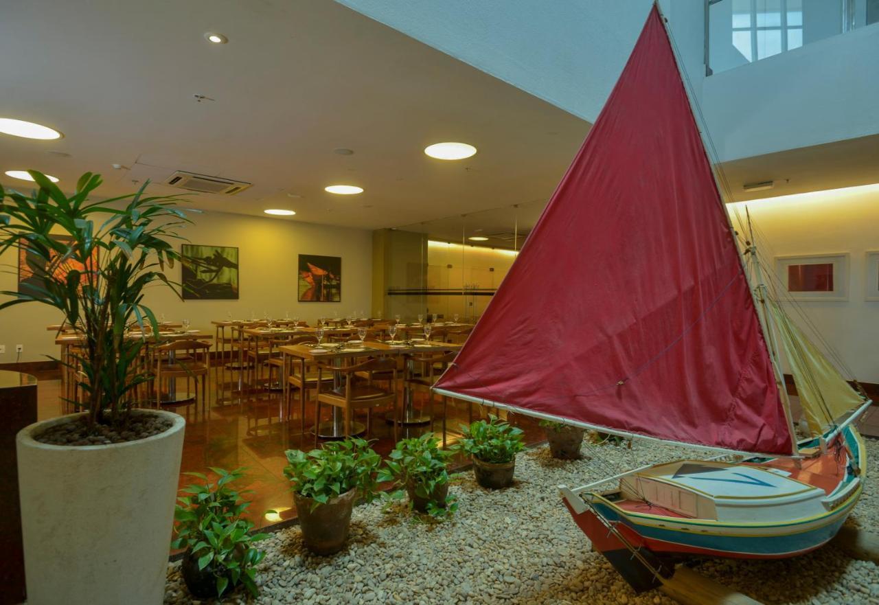 Hotel Luzeiros Sao Luis Экстерьер фото The photo depicts an indoor space, likely a restaurant or dining area. The setting features a modern design with several tables and chairs arranged for dining. In the foreground, there is a decorative sailboat with a prominent red sail, positioned ne